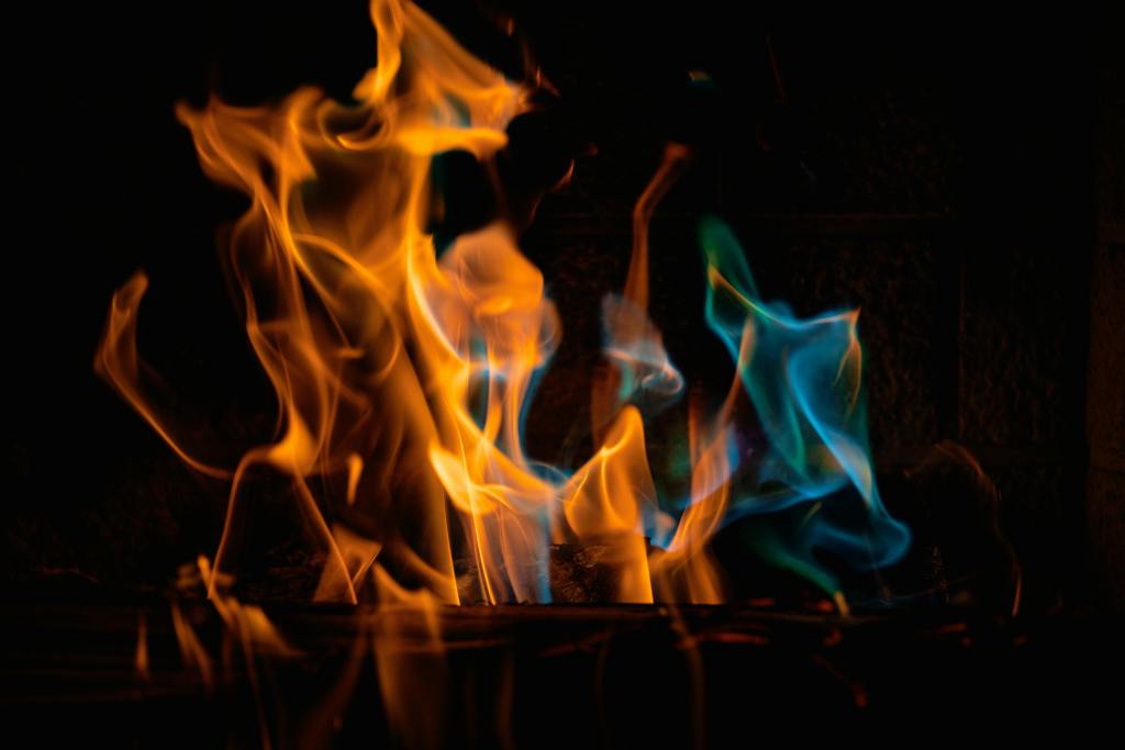 Close-up of orange and blue flames dancing in the dark, symbolizing transformation, passion, and the meeting of sacred elements